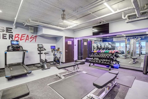 A gym with a variety of equipment including treadmills, weights, and exercise machines.