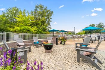an outdoor patio with tables chairs and umbrellas and a fire pit at Sycamore at Tyvola, Charlotte, NC, 28217