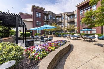 a patio with tables and umbrellas in front of an apartment building at Park & Kingston Charlotte NC 28203