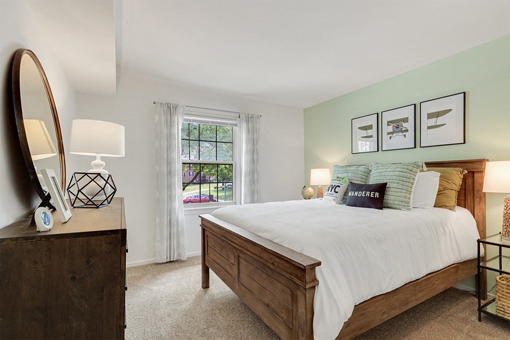 a bedroom with a large bed and a large window  at Courthouse Square Apartments, Towson