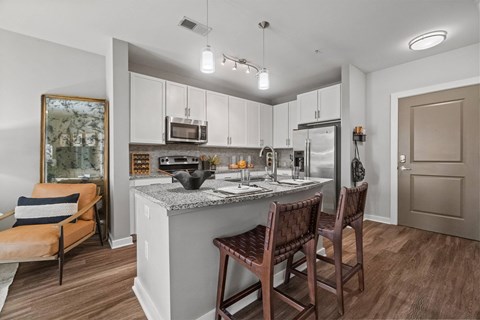 A kitchen with a counter and chairs.