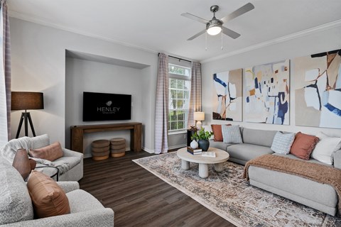 A living room with a grey couch, a white coffee table, and a painting on the wall.
