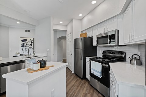 A modern kitchen with white cabinets and stainless steel appliances.