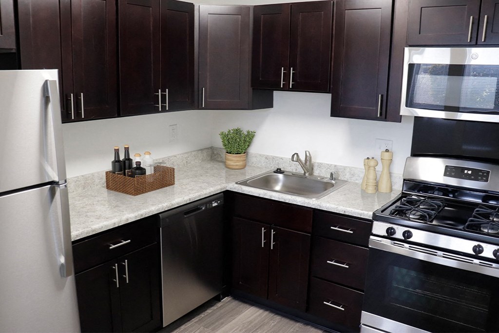 a kitchen with dark cabinets and white countertops at Doncaster Village Apartments, Parkville