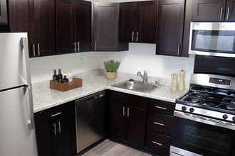 a kitchen with dark cabinets and white countertops a kitchen with dark cabinets and white countertops at Doncaster Village Apartments, Parkville - Photo Gallery