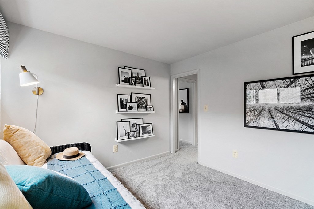 a bedroom with white walls and a bed with a blue blanket at Falls Village Apartments, MD