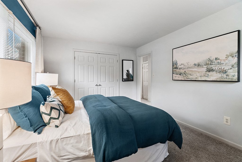 a bedroom with a bed with blue and white bedding and a white door at Falls Village Apartments, MD, 21209