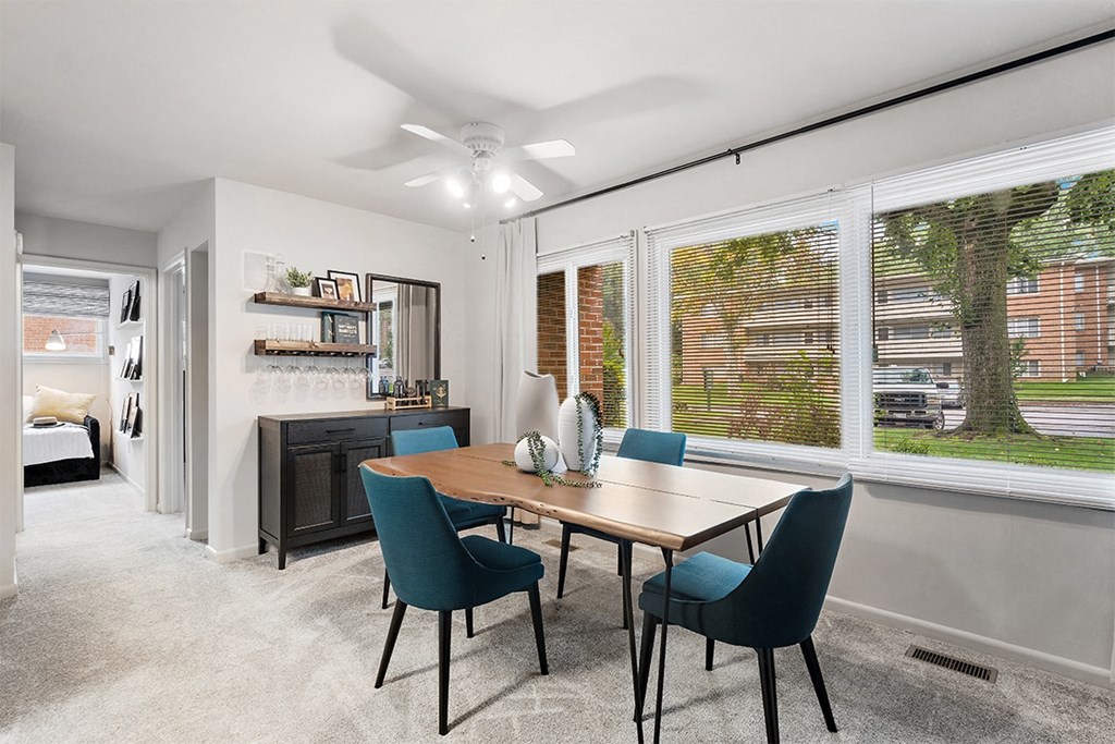 a living room with a large window and a table with chairs at Falls Village Apartments, Maryland, 21209