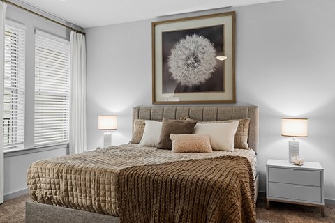 A bedroom with a large bed and a framed picture above it.