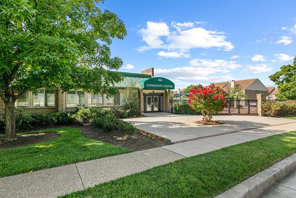 a green building with a sidewalk and trees in front of it at McDonogh Township Apartments, Owings Mills, MD
