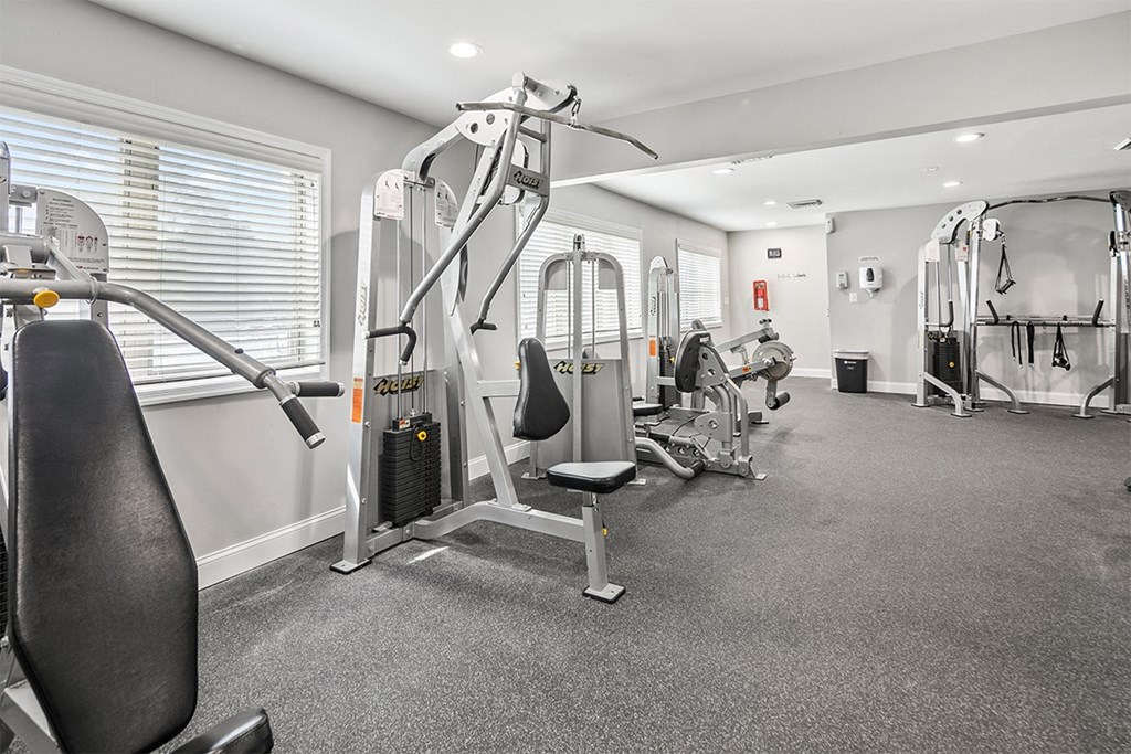 a gym with cardio machines and weights in a room with a window at McDonogh Township Apartments, Maryland