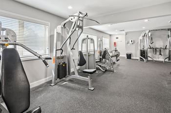 a gym with cardio machines and weights in a room with a window at McDonogh Township Apartments, Maryland, 21117