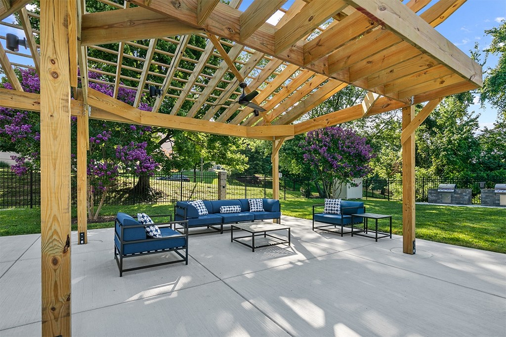 a covered patio with blue couches and a wooden pergola at McDonogh Township Apartments, Owings Mills