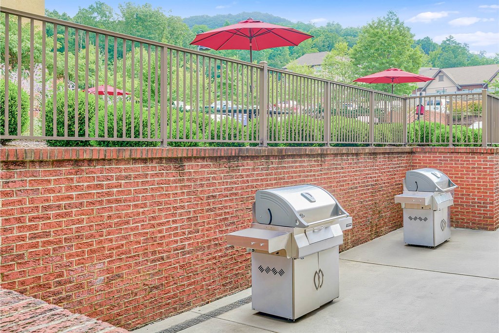 Two trash cans are placed on a sidewalk next to a brick wall at The Lofts at Reynolds Village Apartments, Asheville, NC, 92627