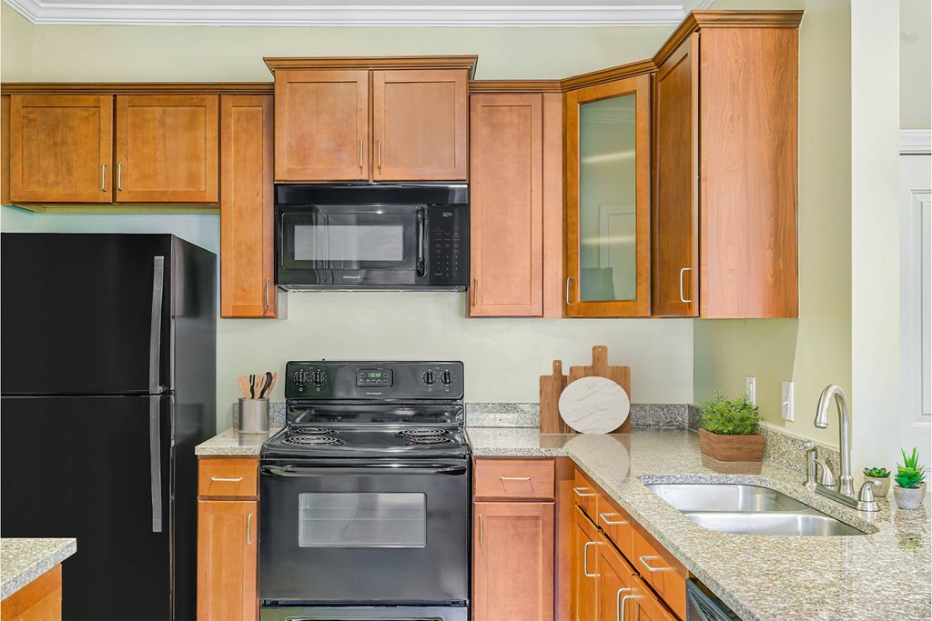 A kitchen with black appliances and wooden cabinets at The Lofts at Reynolds Village Apartments, Asheville, NC