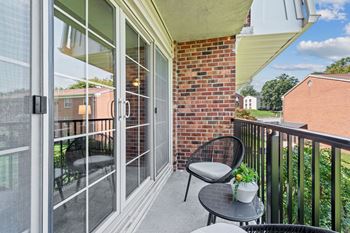 a patio with two chairs and a table on a balcony at Courthouse Square Apartments, Towson, 21286