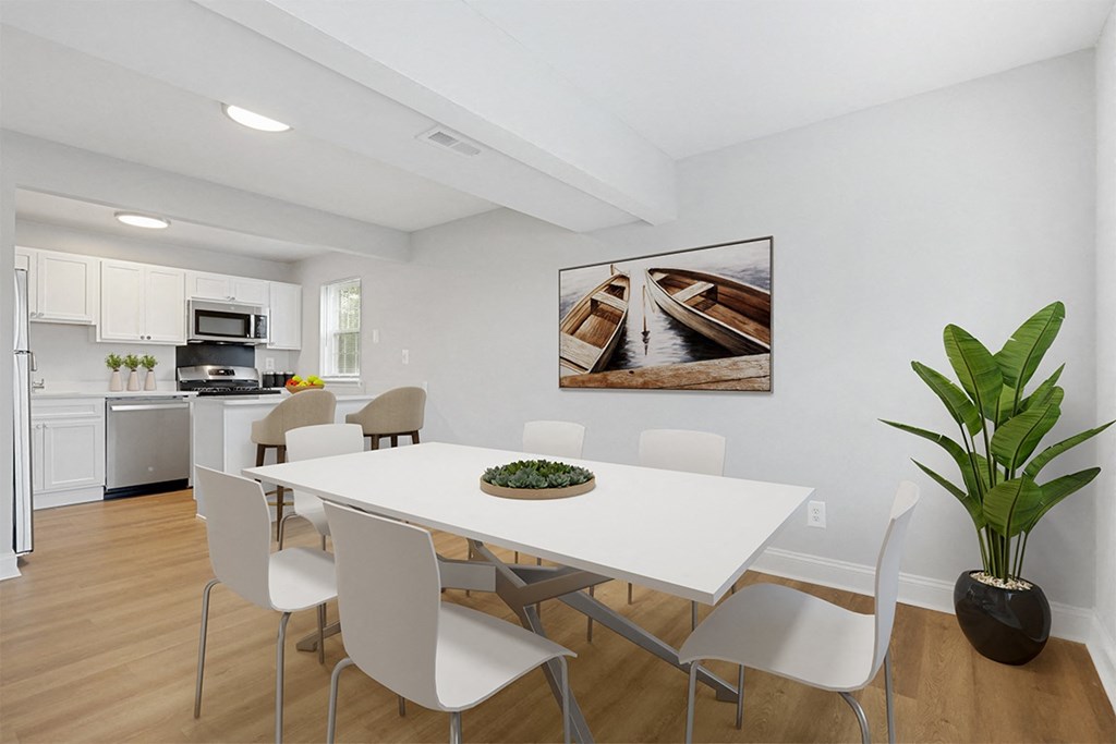 a dining room with a white table and chairs and a white kitchen with stainless steel appliances Kenilworth at Perring Park Apartments, Baltimore, MD 21234