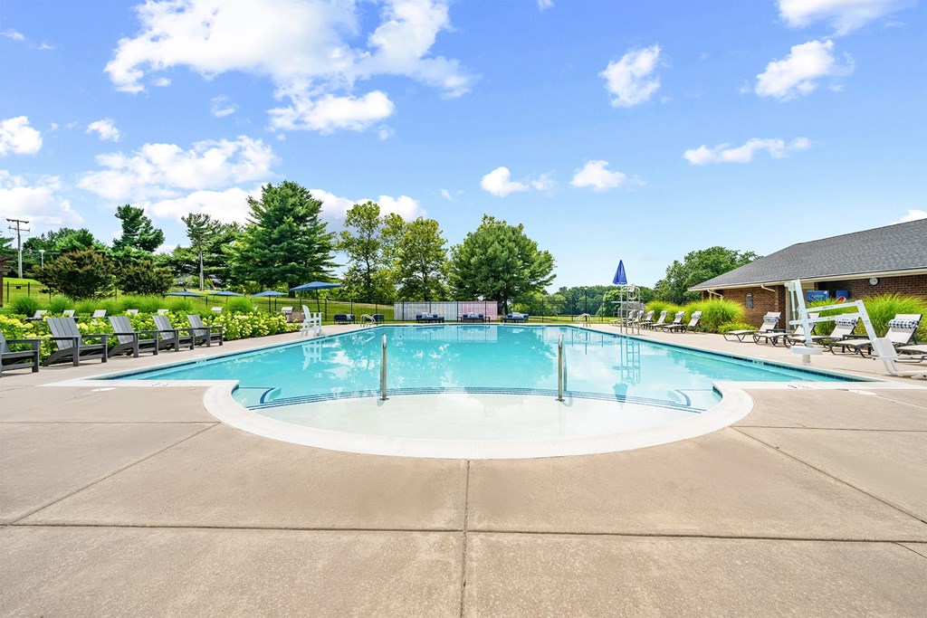 A large outdoor swimming pool surrounded by trees and a building.