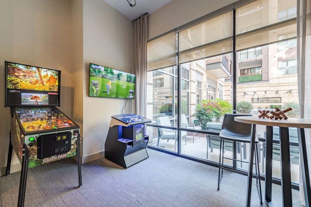 A room with a pinball machine and a TV showing a game at The Edison Lofts Apartments, Raleigh, NC