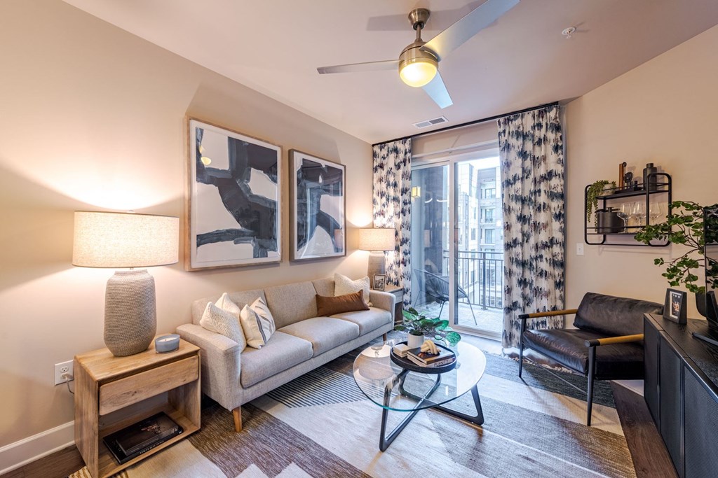 A living room with a couch, a coffee table, and a ceiling fan at The Edison Lofts Apartments, Raleigh