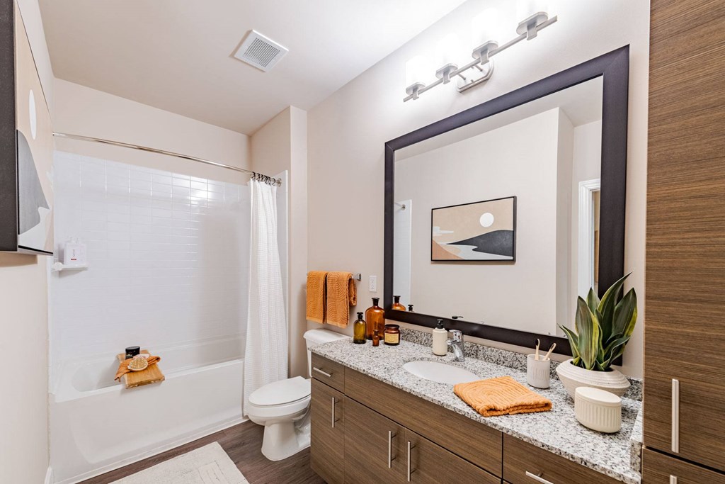 A bathroom with a white tub, sink, and mirror at The Edison Lofts Apartments, Raleigh, NC