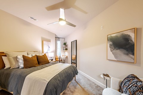 A bedroom with a large bed and a ceiling fan.