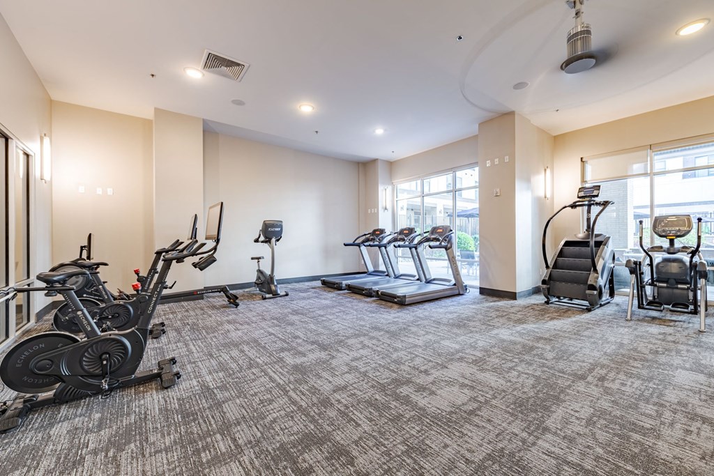 A spacious gym with treadmills, elliptical machines, and stationary bikes at The Edison Lofts Apartments, Raleigh, North Carolina