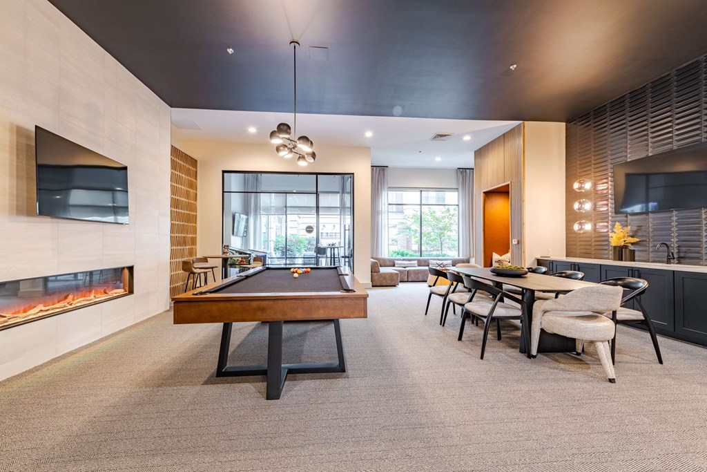 A room with a pool table, a fireplace, and a dining table at The Edison Lofts Apartments, Raleigh, NC