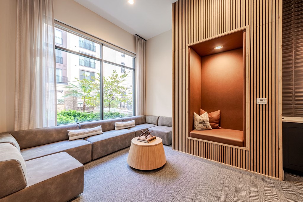 A modern living sitting nook with a large window and a wooden accent wall at The Edison Lofts Apartments, Raleigh, NC