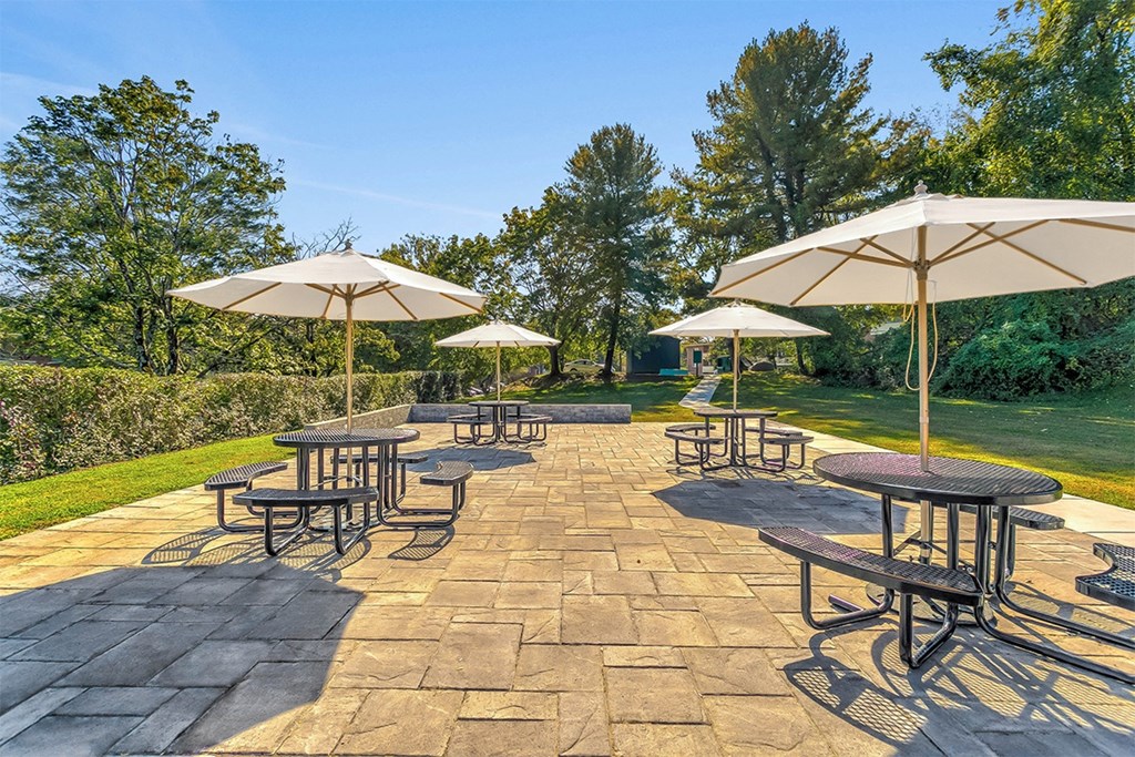 a patio with tables and umbrellas Falls Village Apartments, Baltimore MD