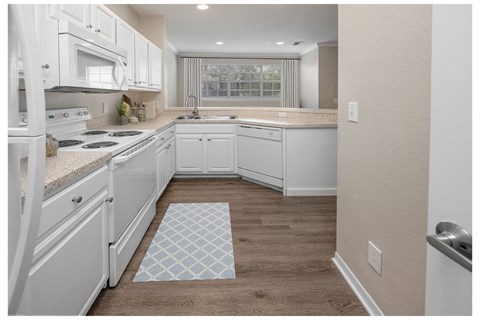 A kitchen with white cabinets and a tile floor mat.