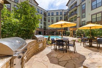 Grilling area with gas grills and patio seating with umbrellas at 1010 Dilworth Apartments, Charlotte, 28204