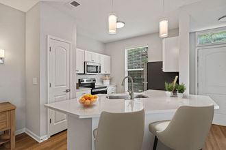 a kitchen with white cabinets and a white island with a bowl of fruit on it