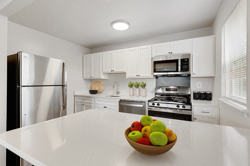a kitchen with white cabinets and a bowl of fruit on the counter a kitchen with white cabinets and a bowl of fruit on the counter Kenilworth at Perring Park Apartments, Baltimore, MD 21234