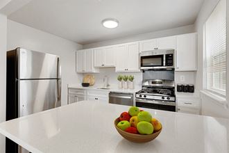 a kitchen with white cabinets and a bowl of fruit on the counter Kenilworth at Perring Park Apartments, Baltimore, MD 21234