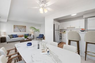a living room and dining room with a white table and chairs a living room and dining room with a white table and chairs at Falls Village Apartments, Baltimore MD
