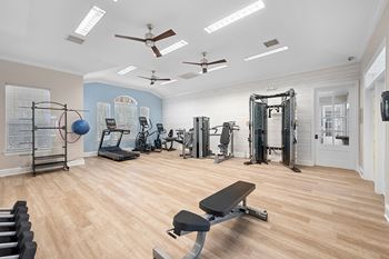 a gym with exercise equipment and ceiling fans