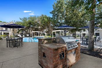 an outdoor patio with a barbecue grill and tables with umbrellas at Sweetgrass Landing, South Carolina