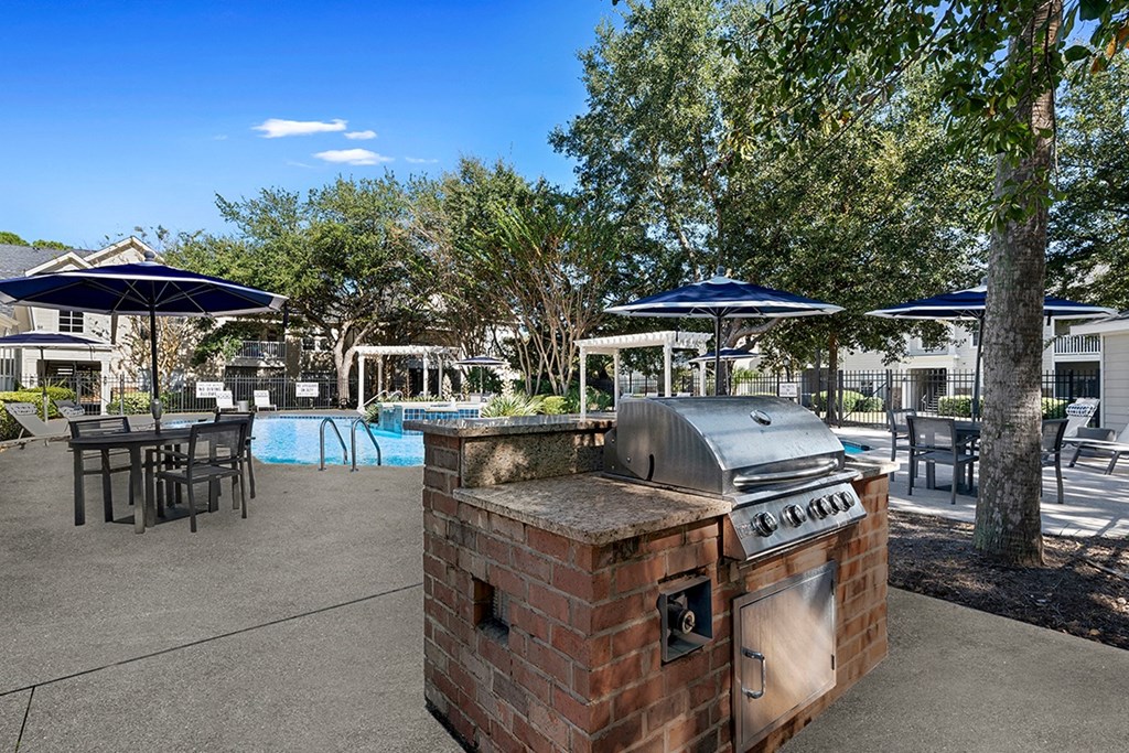 an outdoor patio with a barbecue grill and tables with umbrellas at Sweetgrass Landing, Mount Pleasant