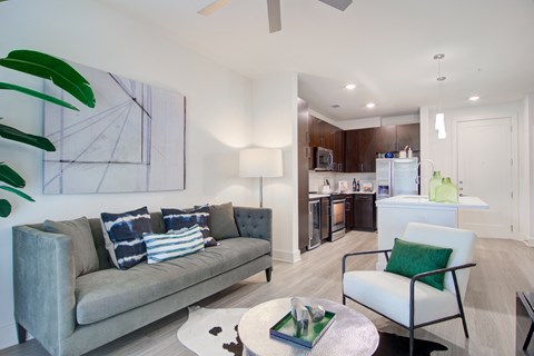 a living room with a couch and chairs and a kitchen