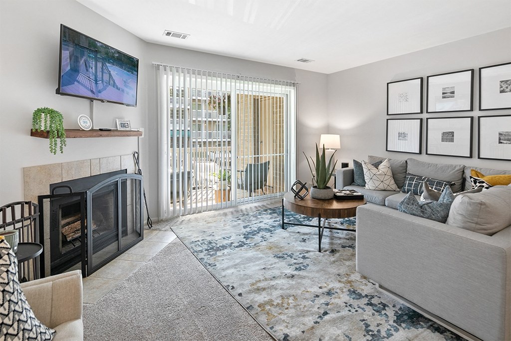 an open living room with a fireplace and a sliding glass door at McDonogh Township Apartments, Owings Mills, MD, 21117