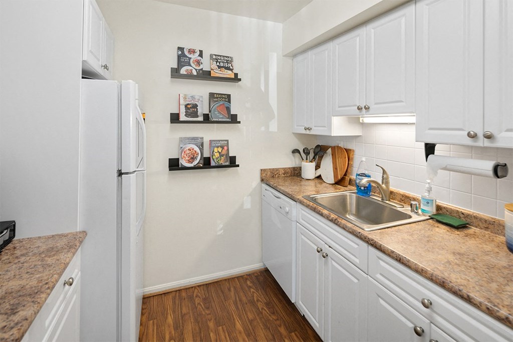 a kitchen with white cabinets and a sink and a refrigerator at McDonogh Township Apartments, Owings Mills, MD