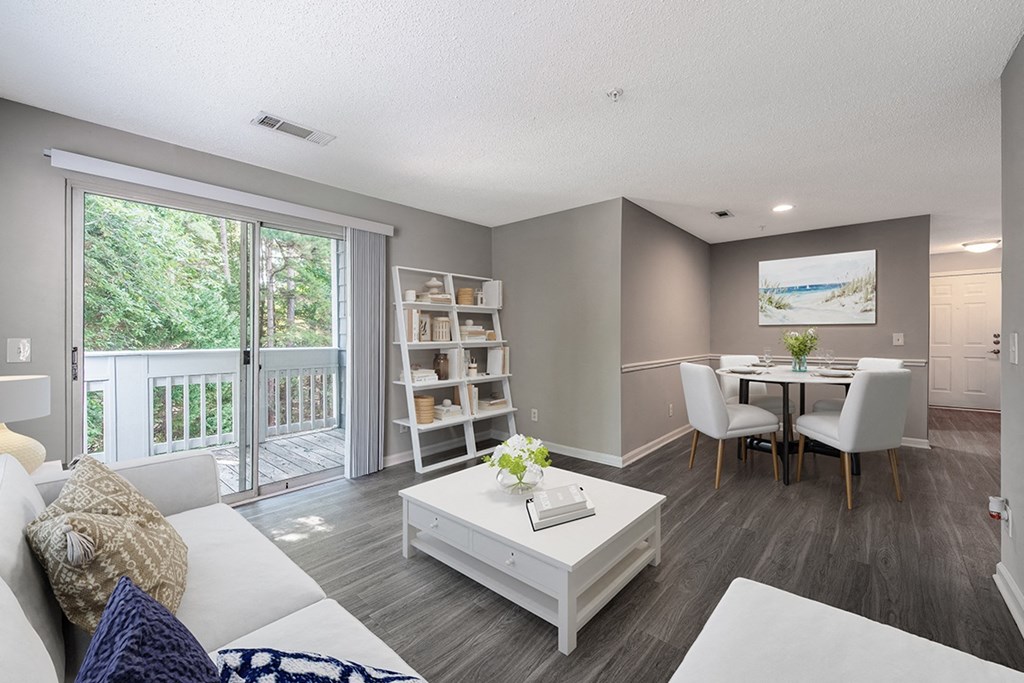 a living room and dining room with a sliding glass door at The Village Apartments, Raleigh, North Carolina