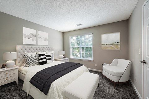 a bedroom with a bed and a chair at The Village Apartments, Raleigh, NC