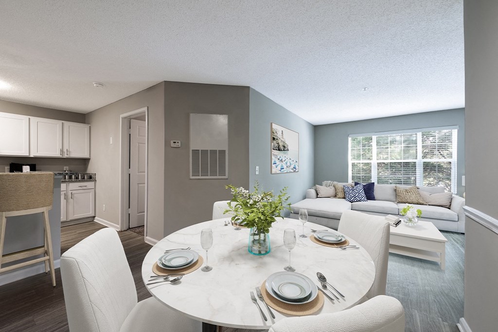 a living room and dining room with a table and chairs  at The Village Apartments, Raleigh, NC