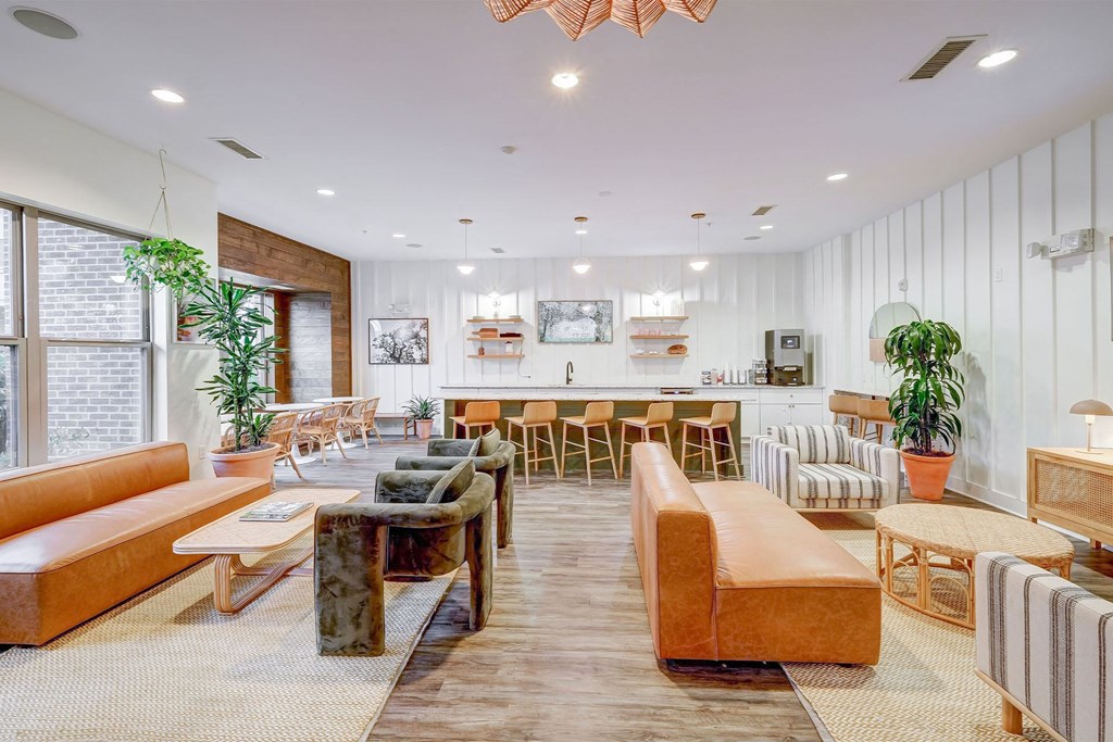 A modern resident clubroom with a variety of seating options and a long wooden table at The Linden Apartments, Davidson