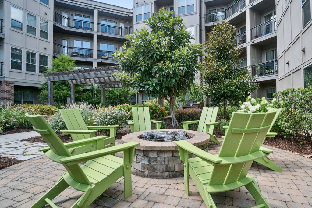 A fire pit surrounded by green chairs in a courtyard at The Linden Apartments, Davidson, 28036