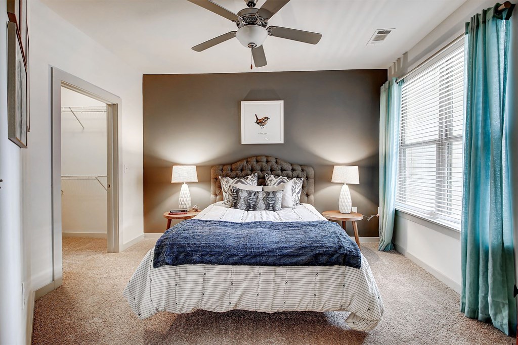 A bedroom with a bed, two lamps, and a ceiling fan at The Linden Apartments, Davidson, NC, 28036