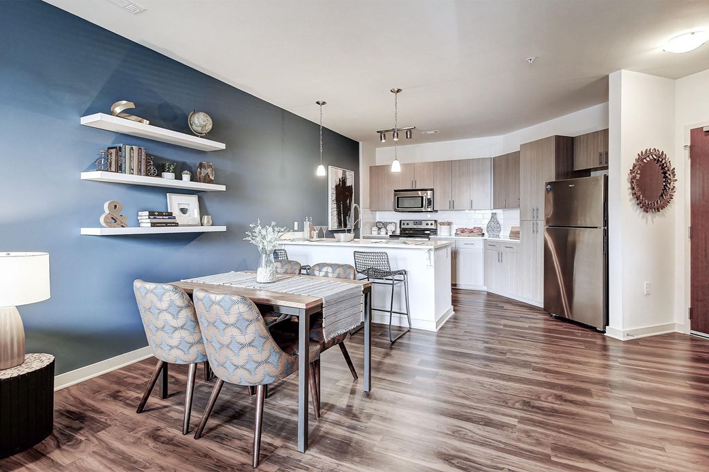 A kitchen with a table and chairs in front of a blue wall at The Linden Apartments, North Carolina