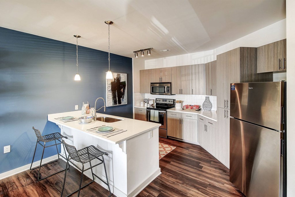 A kitchen with a white island and a stainless steel refrigerator at The Linden Apartments, North Carolina